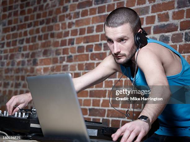 male dj using laptop and decks, wearing headphones - dj decks stock-fotos und bilder