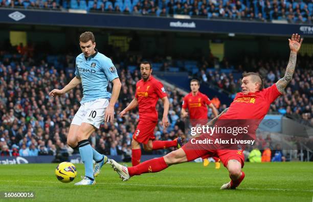 Edin Dzeko of Manchester City goes past the tackle of Daniel Agger of Liverpool to score the opening goal during the Barclays Premier League match...