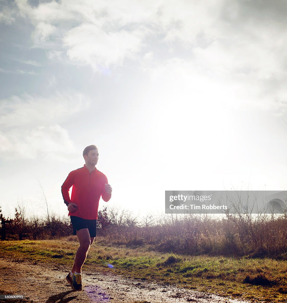 Jogger running on muddy track.