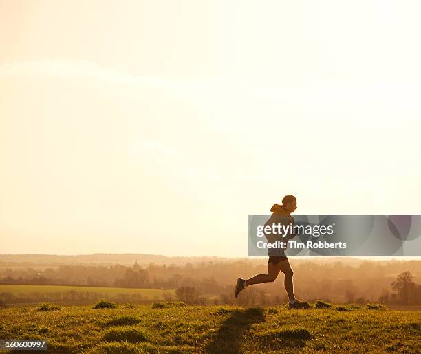 jogger running on hill at sunset. - running man stockfoto's en -beelden