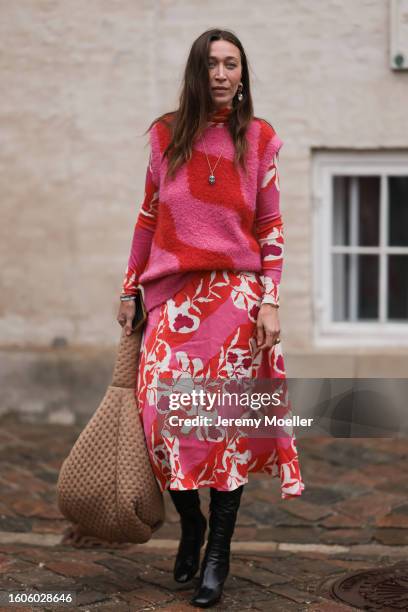 Alana Hadid seen outside Marimekko show wearing golden earrings, big amulet chain with blue details, pink and red colored sweater vest, pink and red...