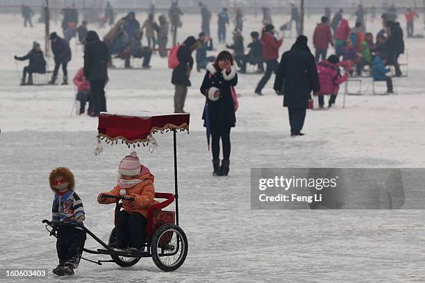 Little girl drives a robot rickshaw on the frozen Houhai Lake during severe pollution on February 3, 2013 in Beijing, China. Houhai Lake is a popular...