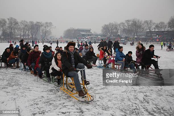 Tourists ride on specially constructed "ice-chairs" on the frozen Houhai Lake during severe pollution on February 3, 2013 in Beijing, China. Houhai...