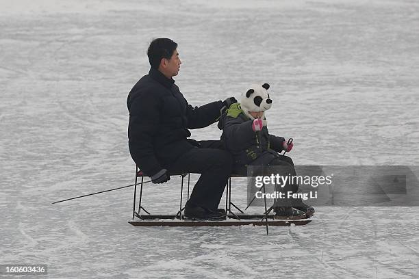 Man and his son ride on specially constructed "ice-chairs" on the frozen Houhai Lake during severe pollution on February 3, 2013 in Beijing, China....