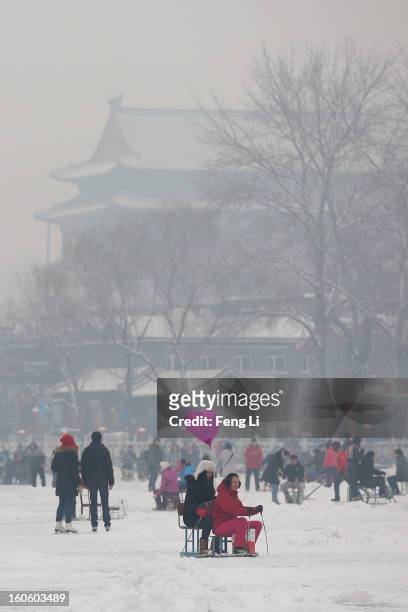 Tourists ride on specially constructed "ice-chairs" on the frozen Houhai Lake during severe pollution on February 3, 2013 in Beijing, China. Houhai...
