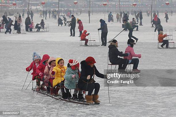 Tourists ride on specially constructed "ice-chairs" on the frozen Houhai Lake during severe pollution on February 3, 2013 in Beijing, China. Houhai...