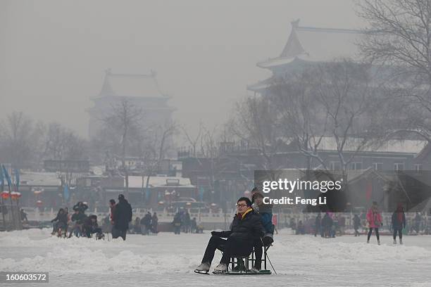 Tourists ride on specially constructed "ice-chairs" on the frozen Houhai Lake during severe pollution on February 3, 2013 in Beijing, China. Houhai...