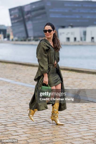 Kika Simonsen wears green belted coat, Delvaux bag, golden boots outside TG Botanical during the Copenhagen Fashion Week Spring/Summer 2024 on August...