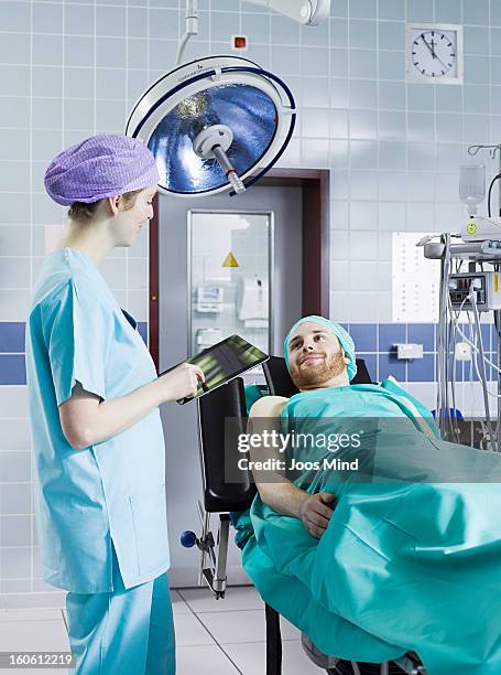 female anaesthetist using digital tablet - man lying on operating table stock pictures, royalty-free photos & images