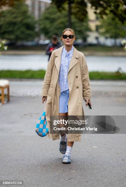 Vera van Erp wears trench coat, blue laced top, shirts, checkered bag outside Stine Goya during the Copenhagen Fashion Week Spring/Summer 2024 on...