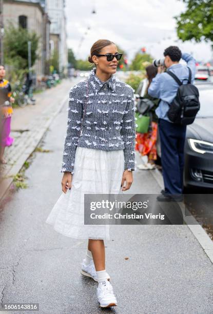 Guest wears white skirt, grey, heart shaped bag Chanel outside Stine Goya during the Copenhagen Fashion Week Spring/Summer 2024 on August 09, 2023 in...