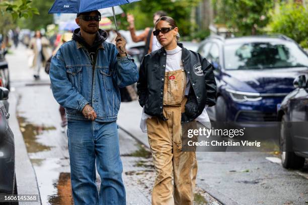 Guest wears denim jacket, jeans and a guest wears beige overall outside Stine Goya during the Copenhagen Fashion Week Spring/Summer 2024 on August...
