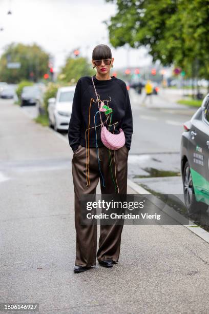 Katya Tolstova wears black jumper, pink bag, brown pants outside Stine Goya during the Copenhagen Fashion Week Spring/Summer 2024 on August 09, 2023...