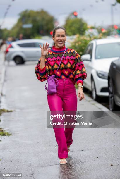 Idalia Salsamendi wears pink heart print jumper, pants, purple bag outside Stine Goya during the Copenhagen Fashion Week Spring/Summer 2024 on August...