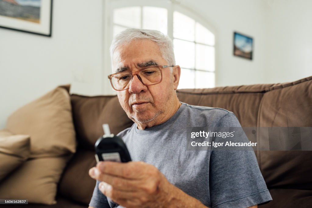 Homem olhando para o resultado do glicosímetro em casa
