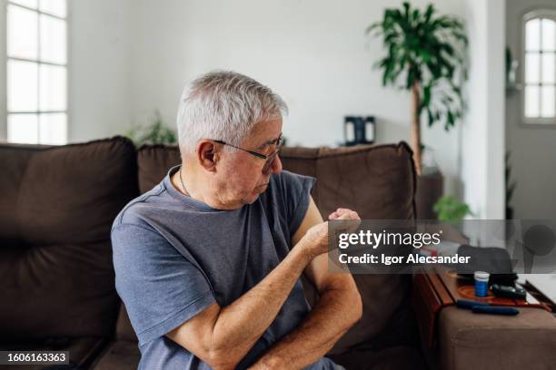 man self giving an insulin injection in his arm at home - injecting pen stock pictures, royalty-free photos & images