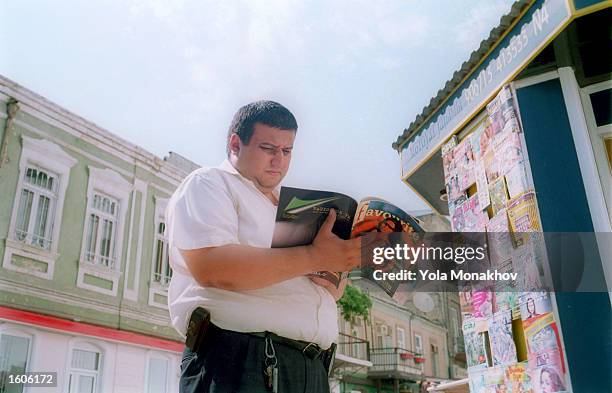 Man looks at a magazine August 1, 2001 at a kiosk in downtown Baku, Azerbaijan. Though the magazine name is in English, the articles are in Cyrillic....