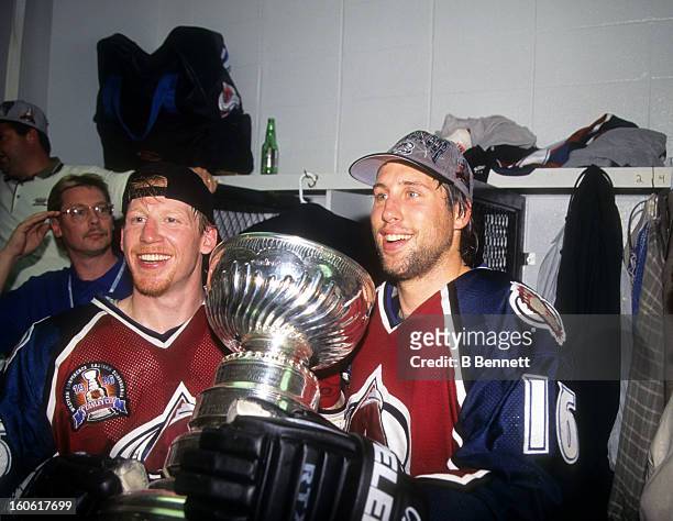 Mike Keane and Warren Rychel of the Colorado Avalanche hold the Stanley Cup in the locker room after the Avalanche defeated the Florida Panthers in...
