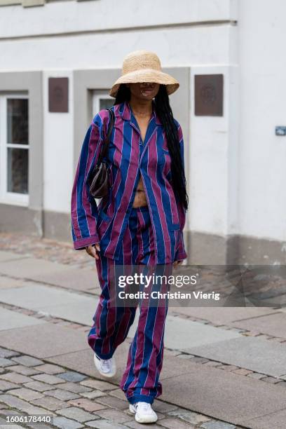 Guest wears beige bucket hat, striped button shirt, pants outside Baum & Pferdgarten during the Copenhagen Fashion Week Spring/Summer 2024 on August...