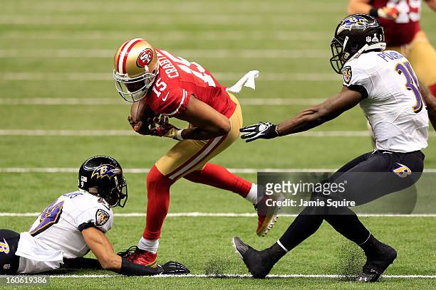 Michael Crabtree of the San Francisco 49ers breaks tackles against Cary Williams and Bernard Pollard of the Baltimore Ravens and runs in for a...