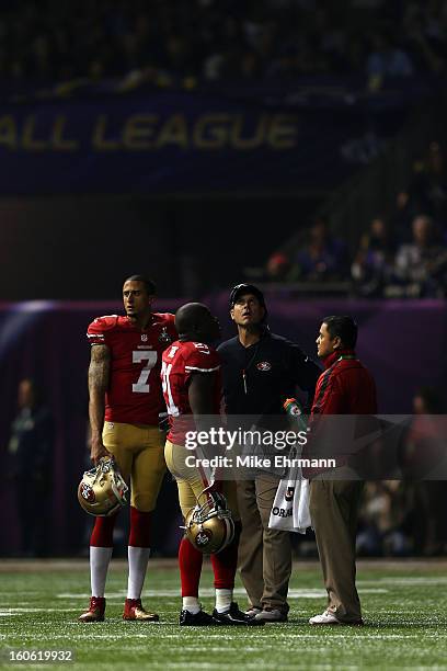 Colin Kaepernick, Frank Gore, and head coach Jim Harbaugh of the San Francisco 49ers wait on the field during a power outage that occured in the...