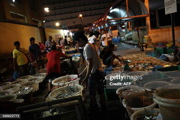 Laborers arrange baskets full of different kinds of fish for customers at the Sandakan central fish market in the Malaysian Borneo state of Sabah on...