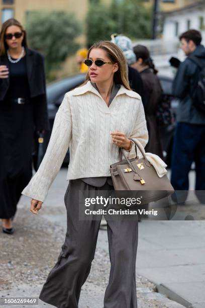 Guest creme white polo with long sleeves, Hermes bag, grey pants outside Munthe during the Copenhagen Fashion Week Spring/Summer 2024 on August 10,...