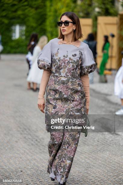 Guest dress & pants with graphic print, green Loewe bag outside Munthe during the Copenhagen Fashion Week Spring/Summer 2024 on August 10, 2023 in...