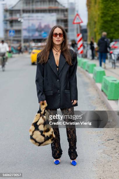 Idalia Salsamendi wears black oversized blazer, laced pants, animal print bag outside Munthe during the Copenhagen Fashion Week Spring/Summer 2024 on...