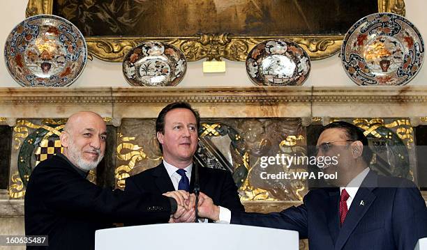 Britain's Prime Minister David Cameron shakes hands with Afghan President Hamid Karzai and Pakistani President Asif Ali Zardari at the Prime...