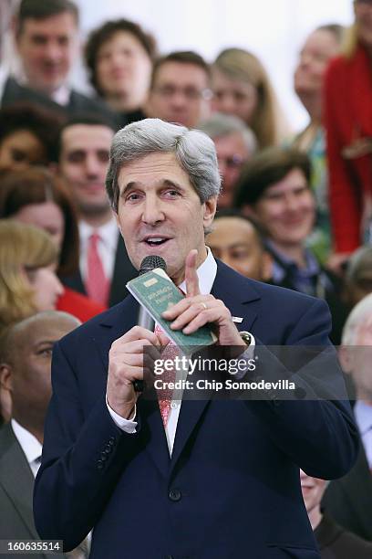 Secretary of State John Kerry holds his first diplomatic passport he received as an 11-year-old boy while making remarks to employees on his first...