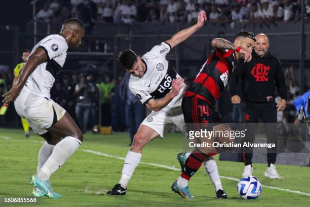 Giorgian De Arrascaeta of Flamengo challenges for the ball with Alejandro Silva of Olimpia during a Copa CONMEBOL Libertadores 2023 round of sixteen...