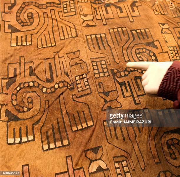 An archaeologist shows the detail of a robe found next to a mummy belonging to the Wari culture , at Waca Pucllana, in Lima 20 October, 2005. The...