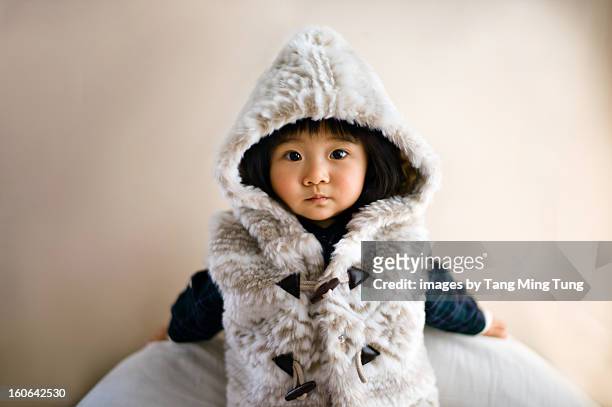 Baby wearing hoody jacket leaning on the wall