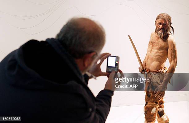 Man takes pictures of a statue representing an iceman named Oetzi, discovered on 1991 in the Italian Schnal Valley glacier, is displayed at the...