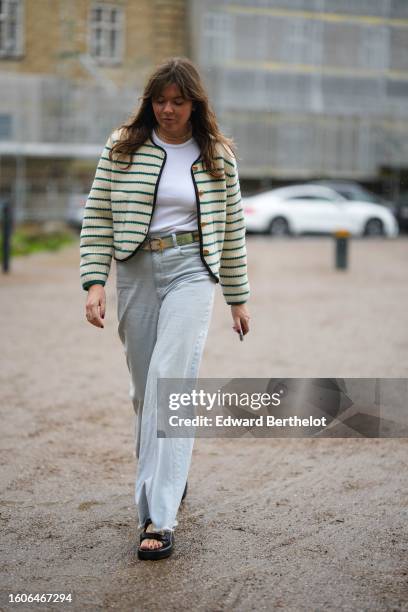 Guest wears a white t-shirt, a white latte and black striped print pattern jacket, a beige matte leather belt, blue faded denim large pants, black...