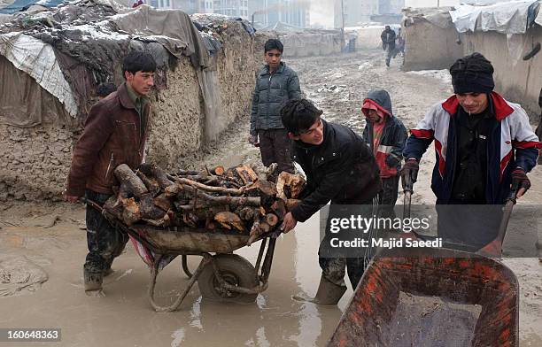 Internally displaced Afghans transport firewood, donated by Danish Refugee Council , through heavy reain and thick mud, at Chamand babrak Camp, on...