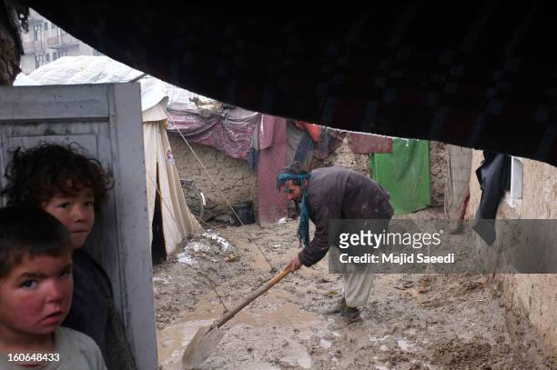 Displaced Afghan man shovels effluent in the heavy rain from outside his family's temporary home at Chamand babrak Camp, on February 3, 2013 in...
