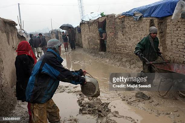 Displaced Afghans clear effluent in the heavy rain from outside their temporary homes at Chamand babrak Camp, on February 3, 2013 in Kabul,...