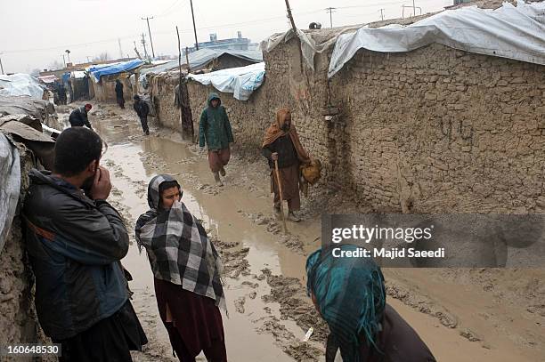 An internally displaced Afghans walk in mud to receive donations from Danish Refugee Council at Chamand babrak Camp, on February 3, 2013 in Kabul,...