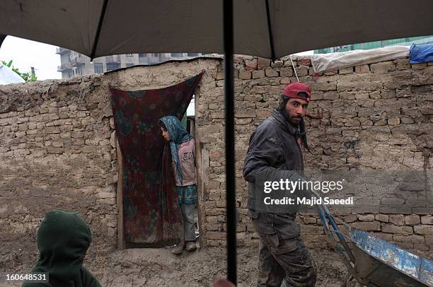 An internally displaced Afghan man pushes a wheelbarrow to receive donations from Danish Refugee Council at Chamand babrak Camp, on February 3, 2013...