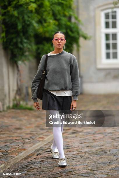 Guest wears pink glasses, multicolored pearls pendant earrings, a white t-shirt, a gray pullover, a dark brown suede large shoulder bag, a dark gray...