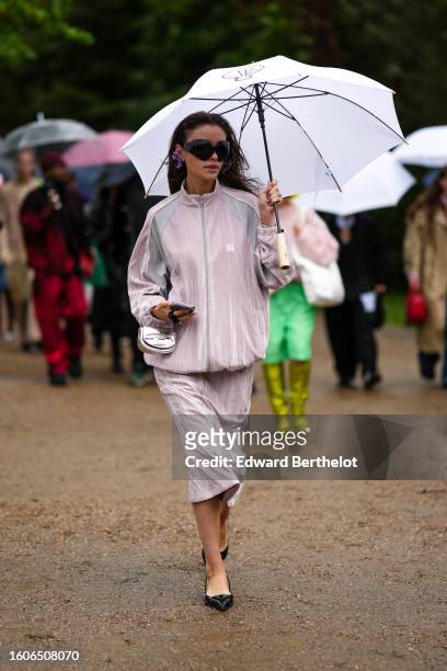 Guest wears a white umbrella, black sunglasses, a pale pink and gray print pattern zipper high neck sport sweater, a matching pale pink and gray...
