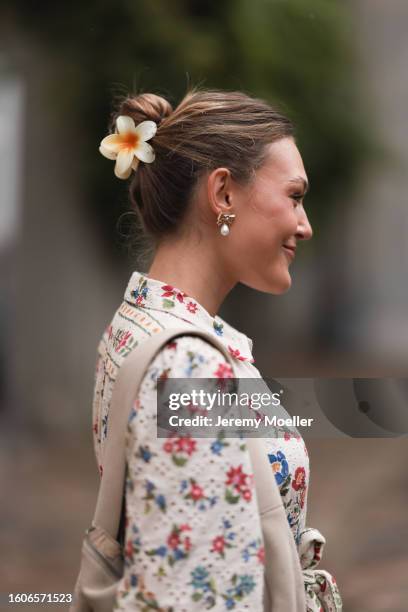 Guest seen outside Marimekko show wearing golden bow earrings with pearl detail, beige shoulder bag and flower printed dress during the Copenhagen...