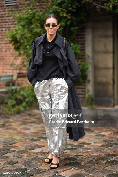 Guest wears black sunglasses, a black buttoned polo shirt, a black long coat, silver shiny cargo large pants, black open toe-cap heels mules ,...