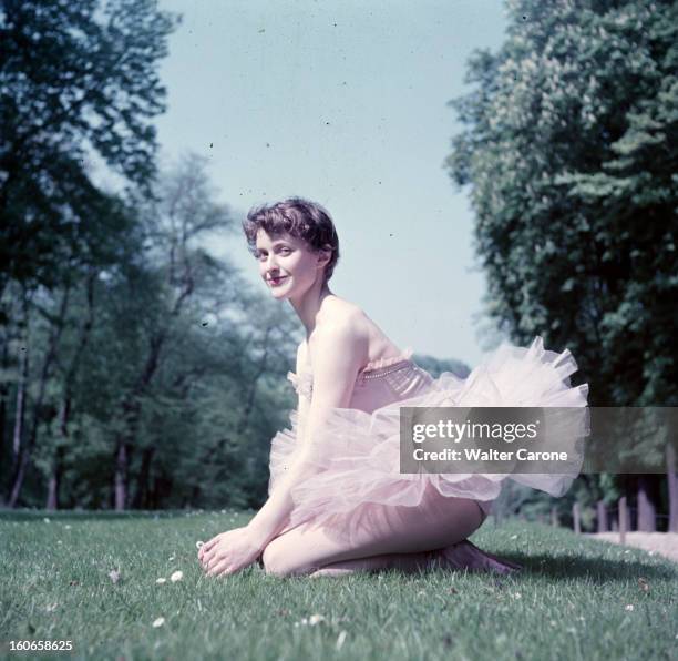 Close-up Of Violette Verdy. Dans un parc, lors d'une séance de portraits, la danseuse Violette VERDY souriante, en tutu, agenouillée dans l'herbe.