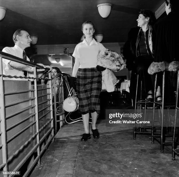 Close-up Of Violette Verdy. Dans une salle de restaurant, portrait de la danseuse Violette VERDY tenant un sac, un manteau au bras.