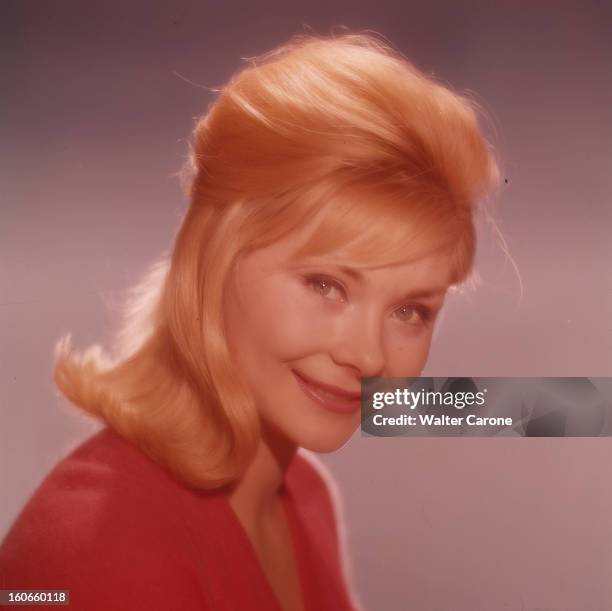 Macha Meril. Portrait studio de l'actrice Macha MERIL, souriante, le buste de profil, portant un chemisier rouge, et les cheveux blonds détachés sur...