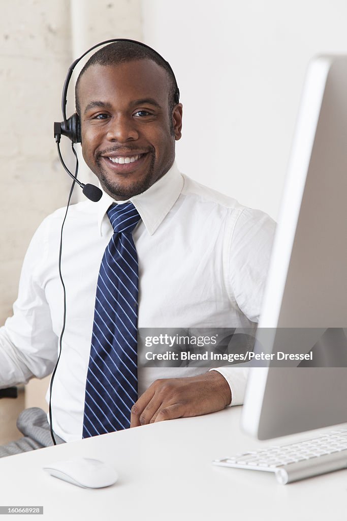 Black businessman in headset working at desk