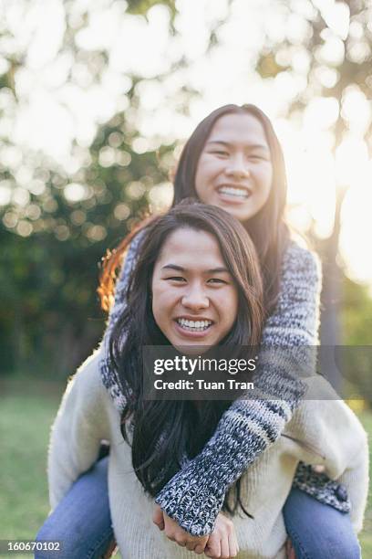 portrait of twin sisters playing at the park - asian twins photos et images de collection